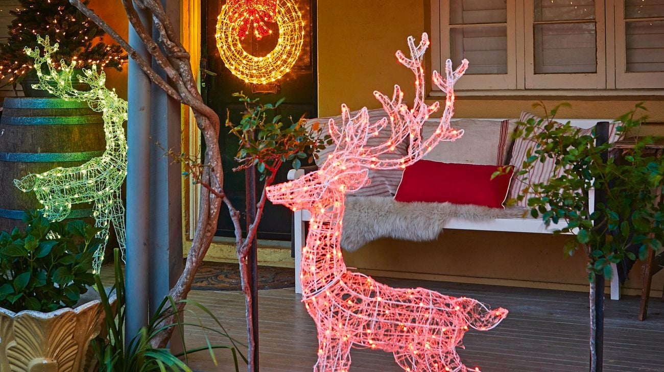 Illuminated reindeer and door decorations on an old style house at night