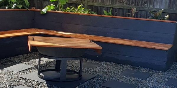 A fire pit in a paved area with timber benches