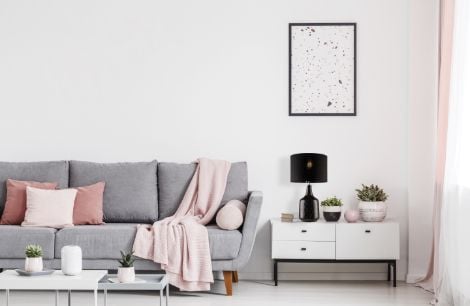 Lounge room with grey lounge and a white table with a lamp and pot plants