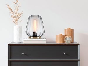 Verve-Design glass lamp on black side table on top of books