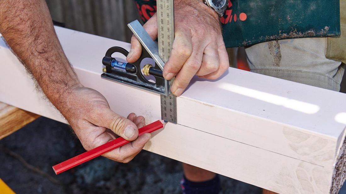 Close up of a Bunnings team member marking a line with a pencil using a ruler and a set square