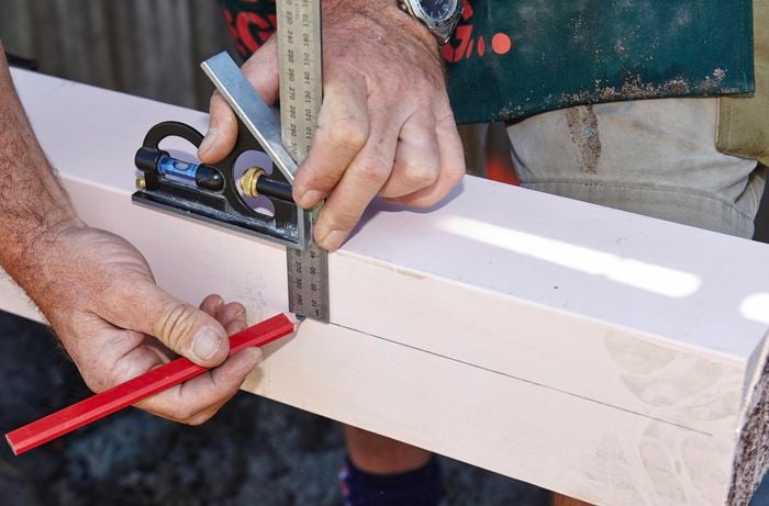 Close up of a Bunnings team member marking a line with a pencil using a ruler and a set square