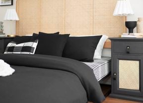 The room has a bed with black bedding and lamps on both bedside tables.