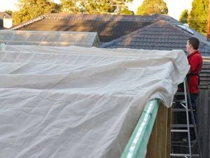 A Bunnings team member installing a shade cloth