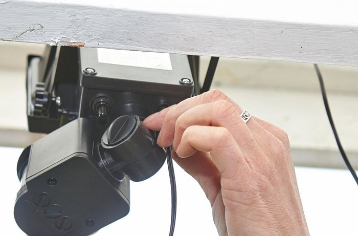 A person plugging a power cable into a sensor light