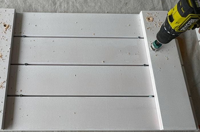 A drill shown drilling holes in a planter bench side panel