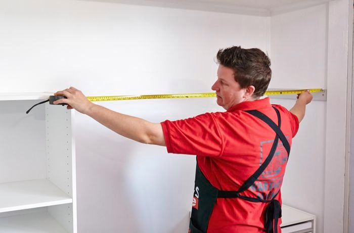 Person using measuring tape to measure inside of wardrobe.