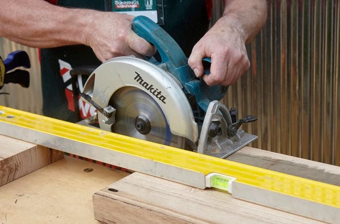 Person cutting bit of timber with circular saw.