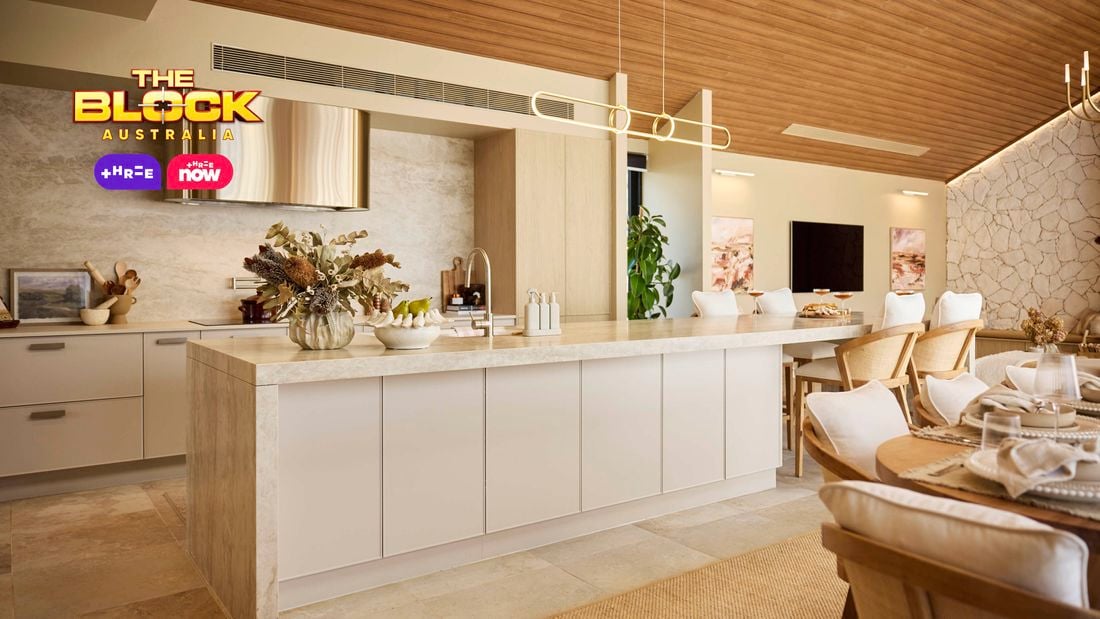 Modern kitchen with marble island, stone feature wall, and dining table.