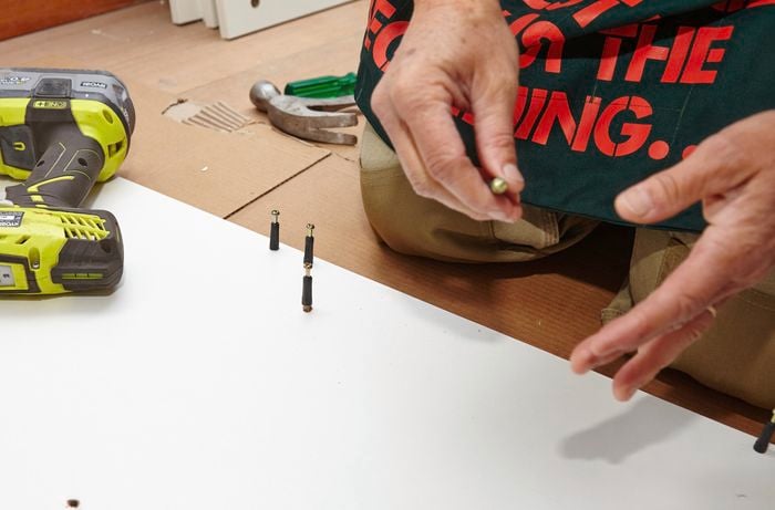 Person inserting pins into side panel of cupboard