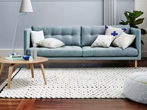 Lounge room featuring couch, coffee table, rug, lamp and fiddle leaf fig.