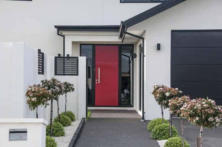Exterior of a modern townhouse painted off-white with a red front door
