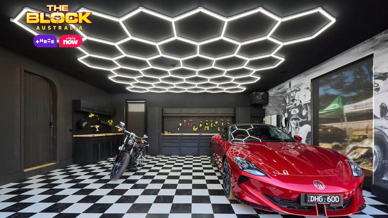 Stylish garage from The Block with checkered flooring, hexagonal LED ceiling lights, a red sports car, and a motorcycle.
