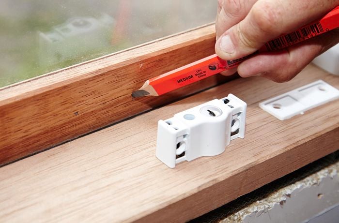 A person marking a window frame with a pencil