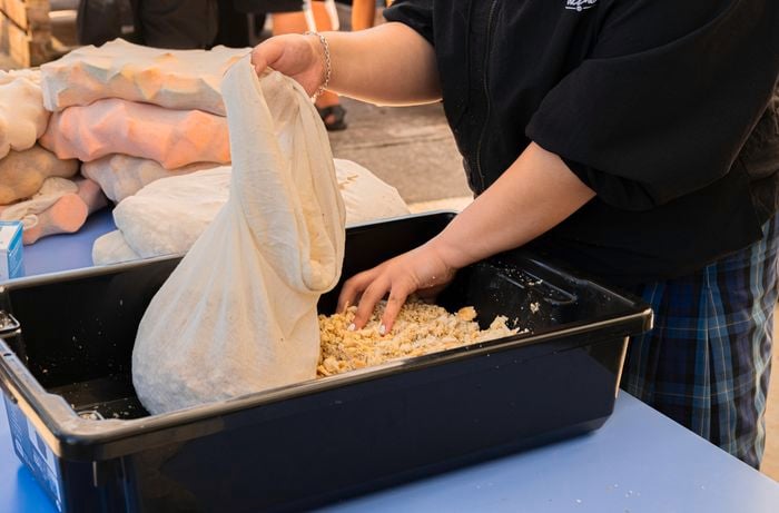 A container filled with food, being put into a cloth bag.