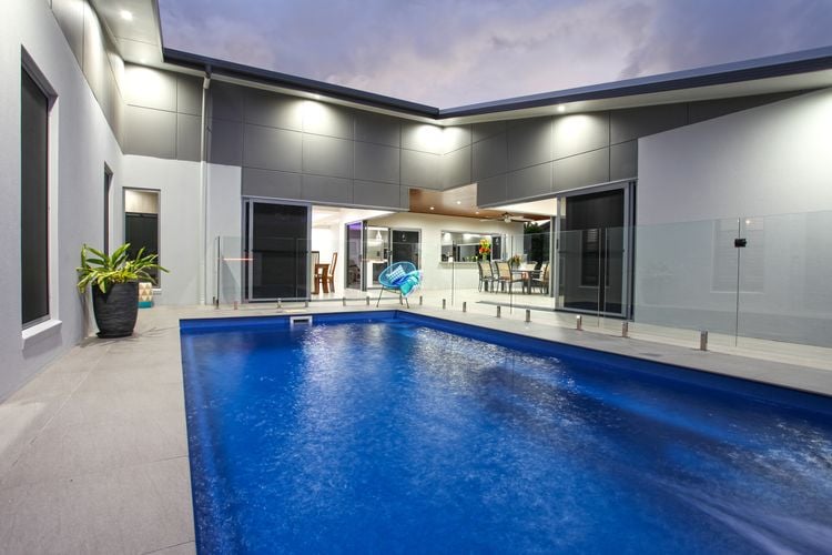 Exterior of a modern house with a swimming pool surrounded by walls with painted cladding panels