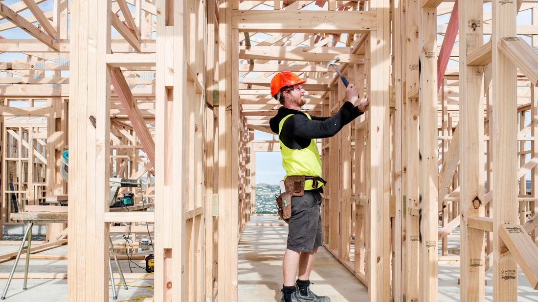 Trade person using a hammer on a house timber frame