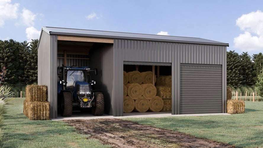 Large grey farm shed with a tractor and hay bales.