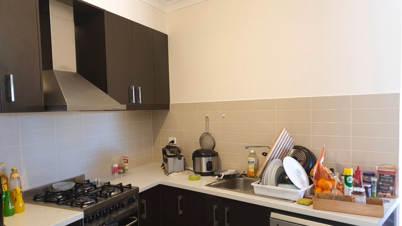 A before image of the renovated kitchen with dark cupboards.