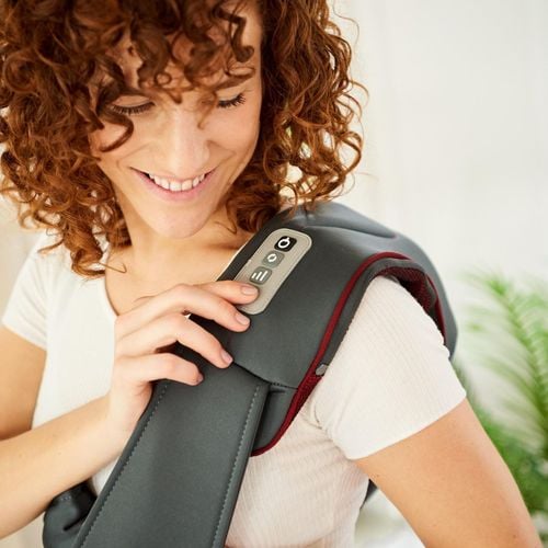 A lady has a heat pack over her should and is smiling