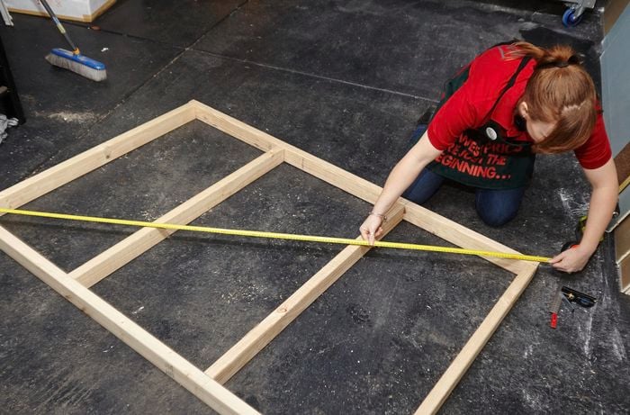 Person measuring corner to corner of timber bedhead frame.