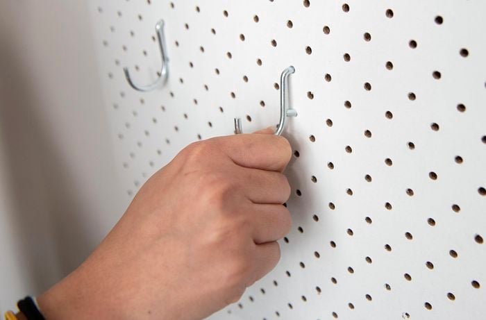 Hooks hanging from holes in pegboard wall.