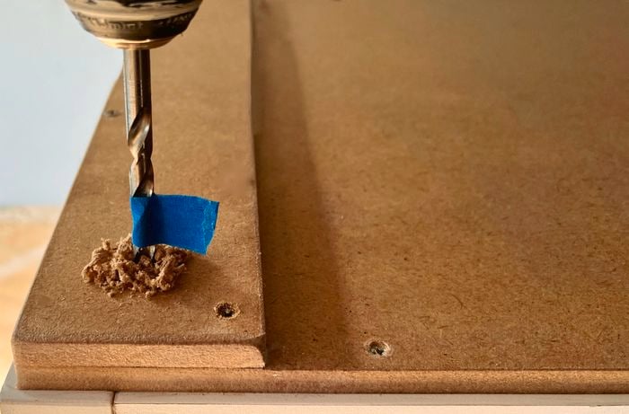 Blue tape on an 8mm bit, pre-drilling into a cabinet base