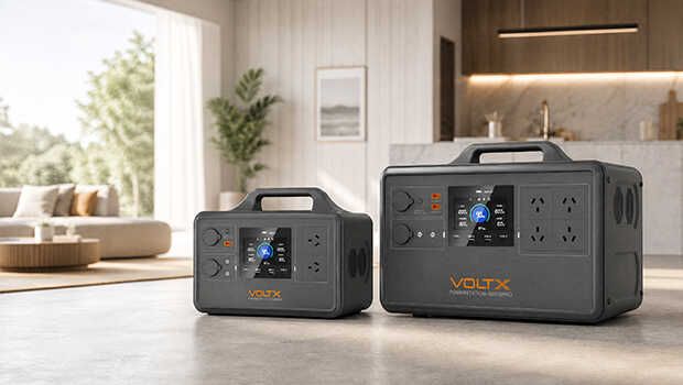 Two portable power stations sitting on the ground in front of a kitchen and living room.