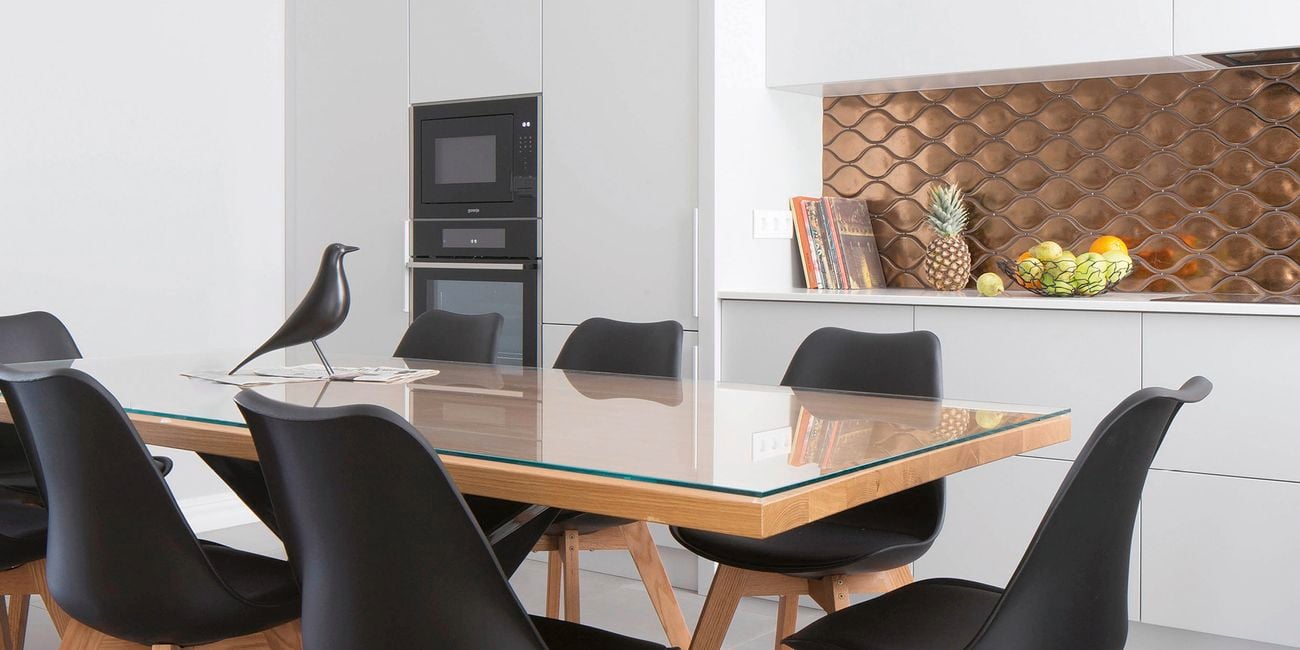 Kitchen with white floor-to-ceiling cabinets and a glass-topped kitchen table