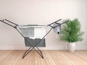Portable clothes drying rack with clothes on it in a living room