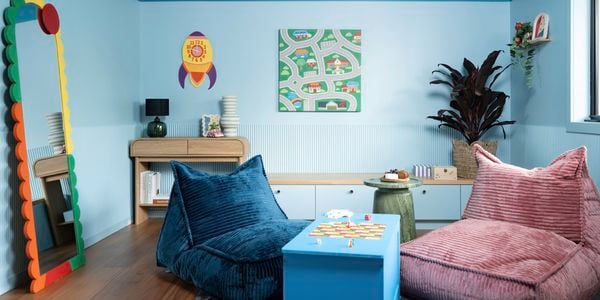 A stylish interior displays a colour-capping paint design with a dark blue upper wall and scalloped moulding, paired with lighter blue walls and vibrant furnishings.