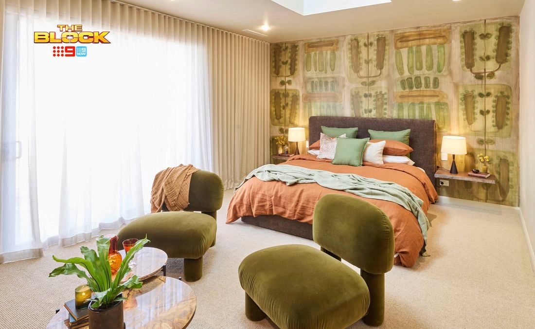 Bedroom with green chairs, patterned feature wall, and earthy-toned bedding.