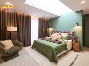 Bedroom with green accent wall, patterned headboard, and earthy decor.