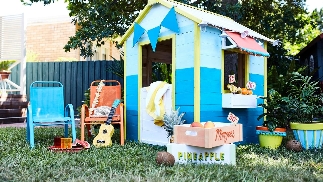Kids cubby house with small recliner chairs, and decorative items out front.