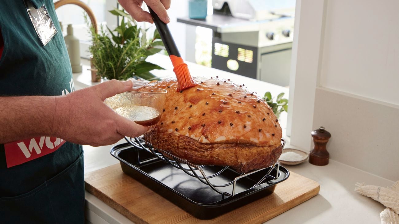 A Bunnings employee uses a brush to baste the ham with glaze.