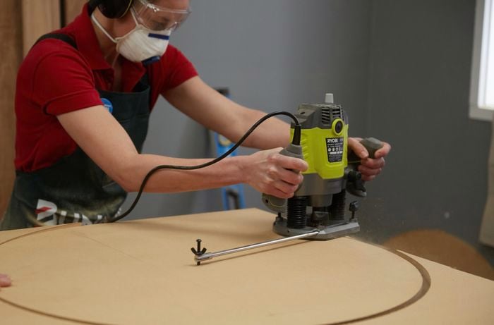Person using router to cut circular tabletop out of timber
