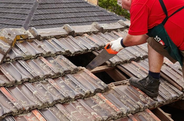 A tile batten being sawed through by a Bunnings team member standing on the roof