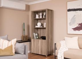 A room with two sofas, a painting, and a half-door storage cabinet by a heat pump.