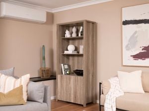 A room with two sofas, a painting, and a half-door storage cabinet by a heat pump.