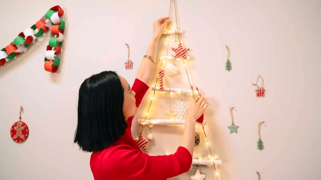 Lady hanging christmas lights on small Christmas tree