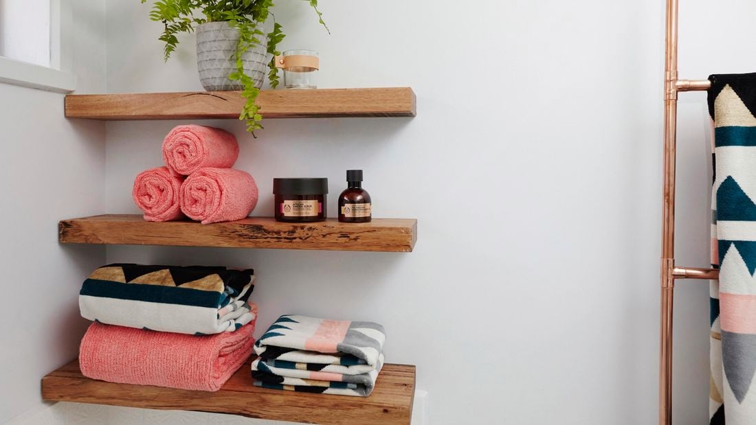 Timber wall shelves with towels and bathroom products sitting on them.
