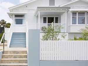 Front view of a modern house with green bushes and small trees planted in the front yard