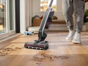 Person using a stick vacuum inside a house