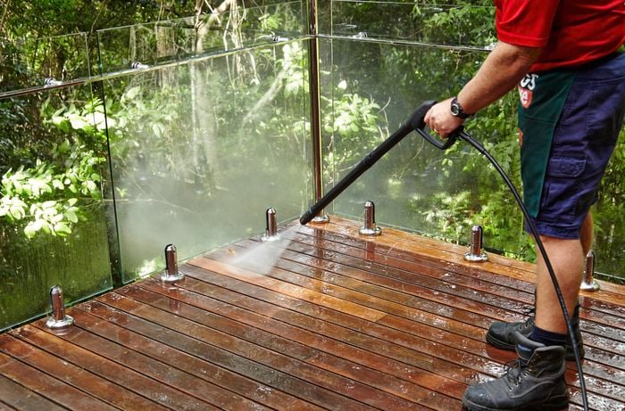 Person cleaning a deck with a high pressure hose
