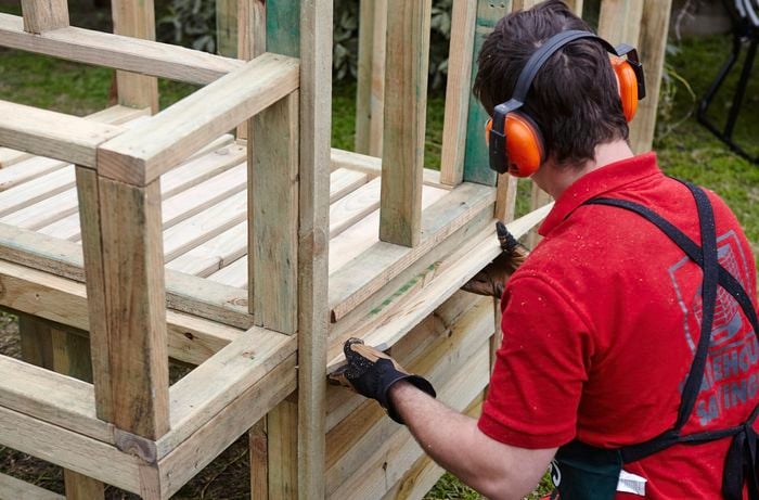 The entrance to the roosting coop being attacked to the wooden frame by a Bunnings team member