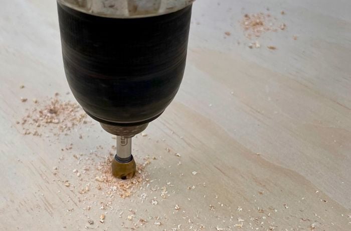 A drill drilling a screw into a panel of wood