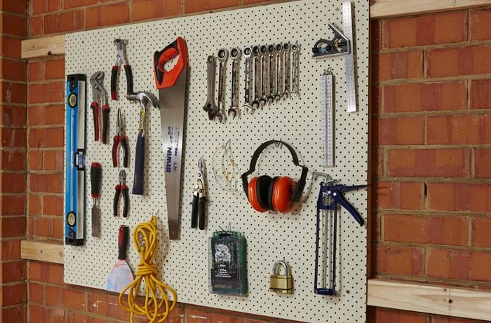 A completed pegboard tool holder mounted on a brick wall
