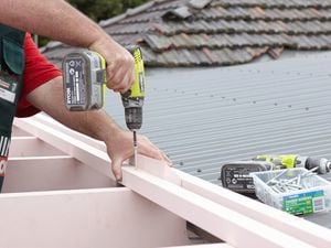 Person attaching shade battens to roof beams on a pergola