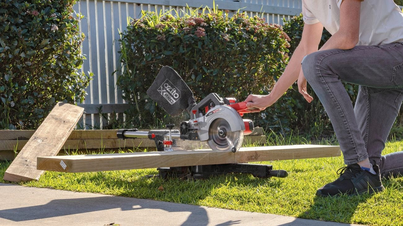 Sliding mitre saw cutting piece of timber.