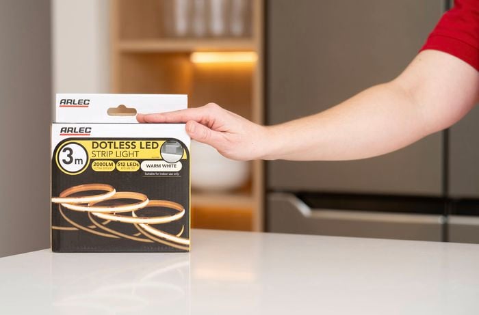 A person holds a box of energy- efficient LED strip light in warm white, designed for indoor use.  